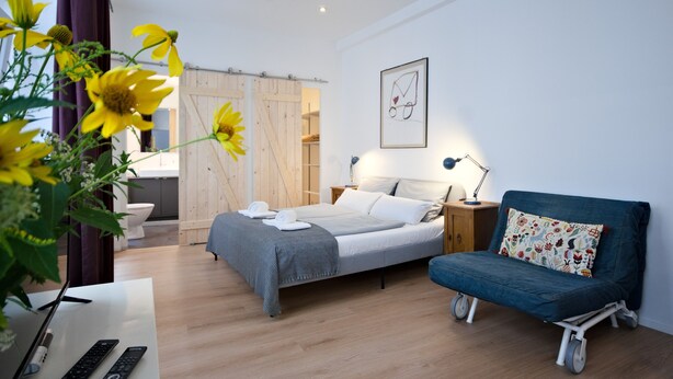 Una camera da letto moderna con un letto, un comodino, una lampada e un divano blu.