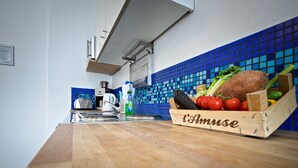 Cucina con piano di lavoro in legno, un tostapane, un bollitore e una scatola di verdure fresche.