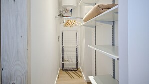 Una cabina armadio stretta con un'asta appendiabiti, scaffali e un termosifone.