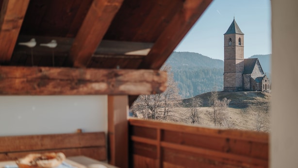 A rustic wooden interior with a view of a church and mountains.