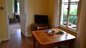 Quarto com uma mesa de madeira, televisão e janela com cortinas.