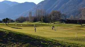 Um campo de golfe com um clube, rodeado por montanhas.