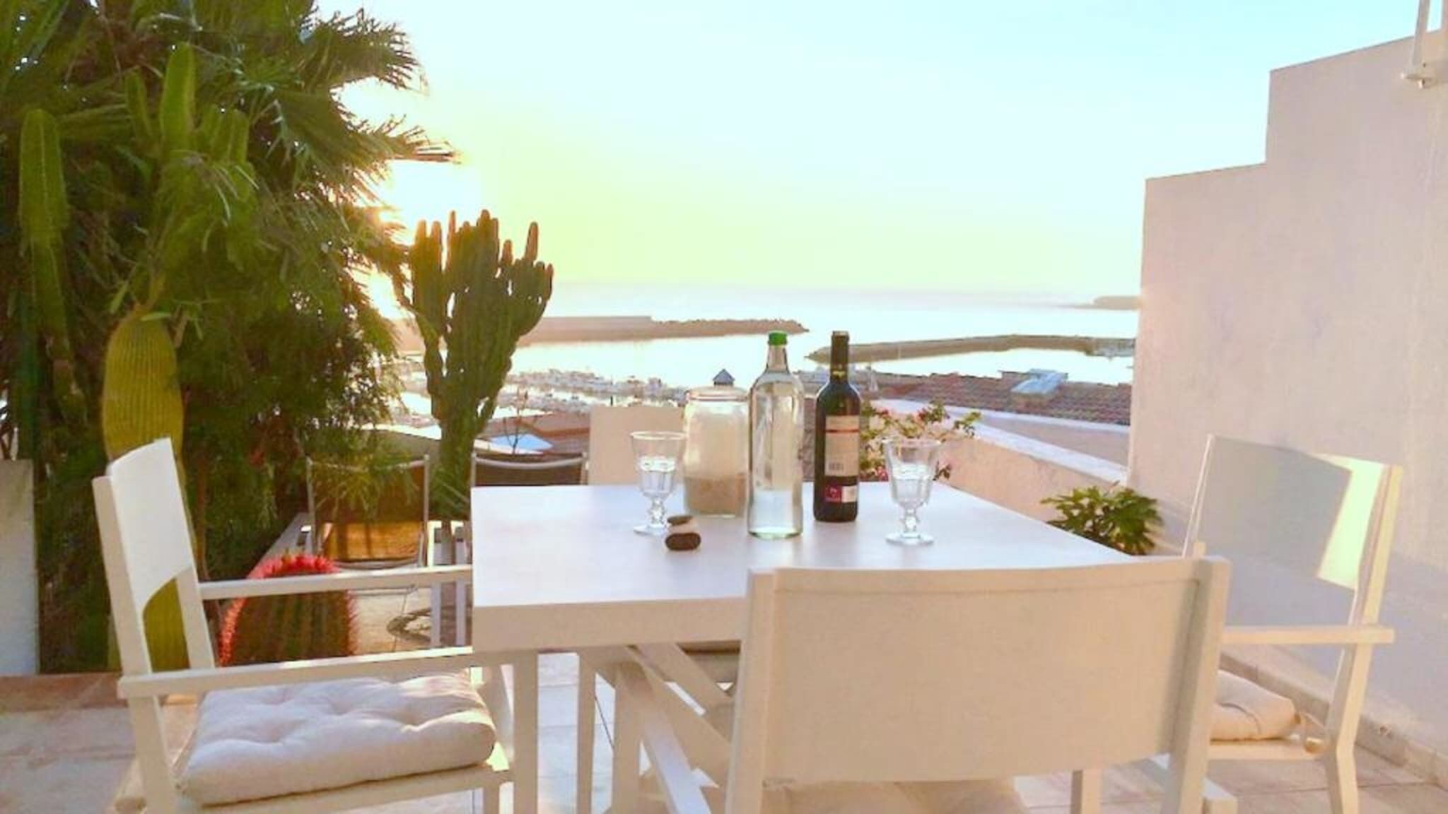 A table set for two with a view of the sea and cityscape.