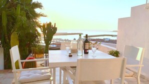 A table set for two with a view of the sea and cityscape.