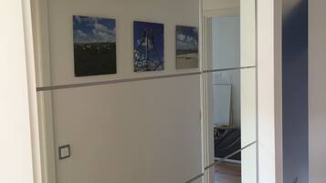 A room with a large mirror reflecting a beach scene, a bed, and a door.