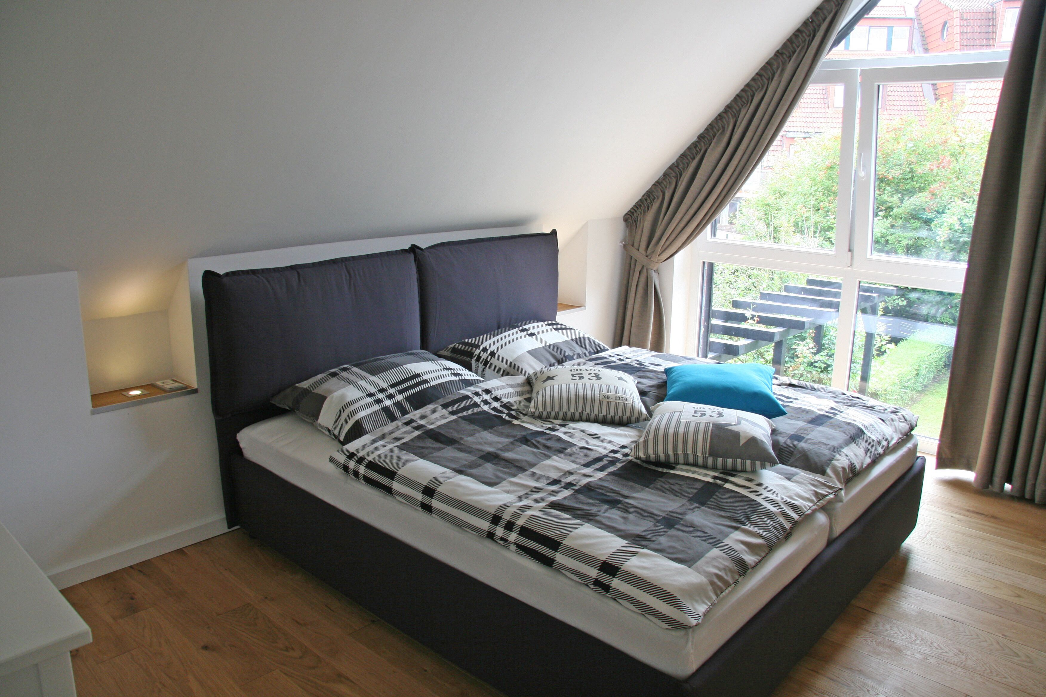 Una camera da letto moderna con un letto grande, un comodino e una finestra con tende.