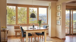 A dining area with a wooden table, chairs, and a vase with flowers. - Welcome to Paradise (Bled)