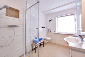 A modern bathroom with a glass-enclosed shower, a toilet, a sink, and a bench with towels. - Apartment on the Zugspitze (Grainau)