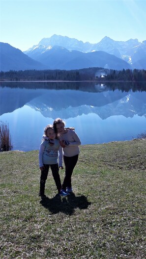 Two people standing by a calm lake with mountains in the background. - Apartment on the Zugspitze (Grainau)