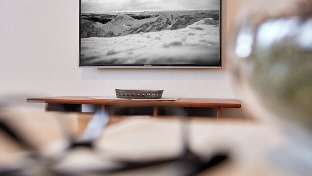 A television mounted on a wall displaying a mountainous landscape. - Apartment on the Zugspitze (Grainau)