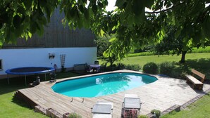A backyard with a wooden deck, a swimming pool, and outdoor furniture. - Vacation on the farm in beautiful Koesslarn in Lower Bavaria (Kößlarn)