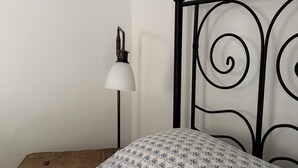 A bed with a patterned pillow, a bedside lamp, and a wooden nightstand.