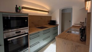 A modern kitchen with built-in appliances, a wooden countertop, and a small island with a sink.