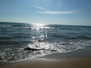 Ein Strand mit sanft anschwellenden Wellen unter blauem Himmel.