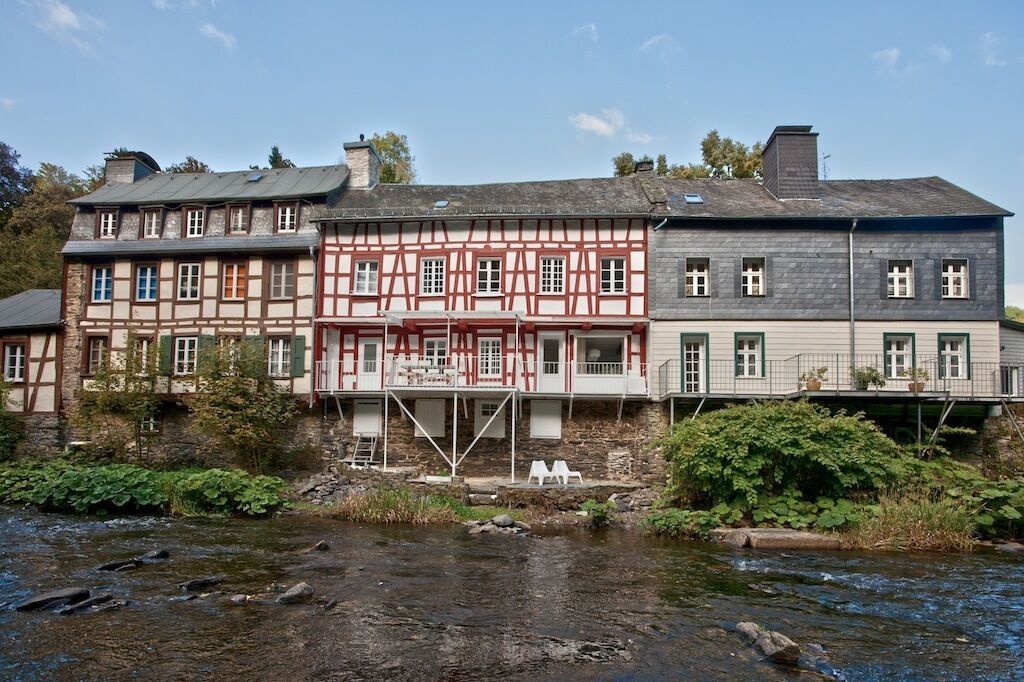 Ein traditionelles Fachwerkhäuschen mit einem Fluss davor.