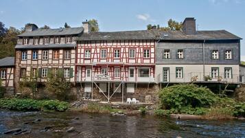 Ein traditionelles Fachwerkhäuschen mit einem Fluss davor.