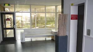 Zona de recepción con un banco, un letrero que indica la entrada al UIT y vistas al exterior a través de amplias ventanas.