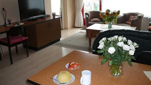 Una sala de estar con televisor, una mesa de comedor con comida, un sofá y una mesa de centro.