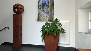 A room with a large potted plant, a globe sculpture, and a painting of flowers. - HAARDTER WINZER (Whg. 4) renovated and lovingly decorated "Pfalzcard-Partner" (Neustadt an der Weinstraße)