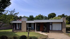 Una casa moderna con facciata in mattoni, ampie finestre e un portico coperto.