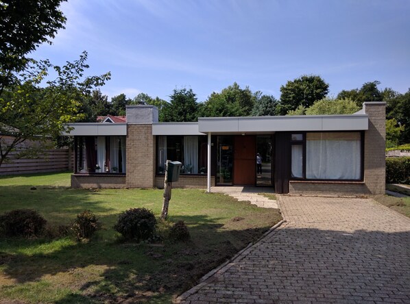 A modern house with a brick exterior, large windows, and a covered porch.