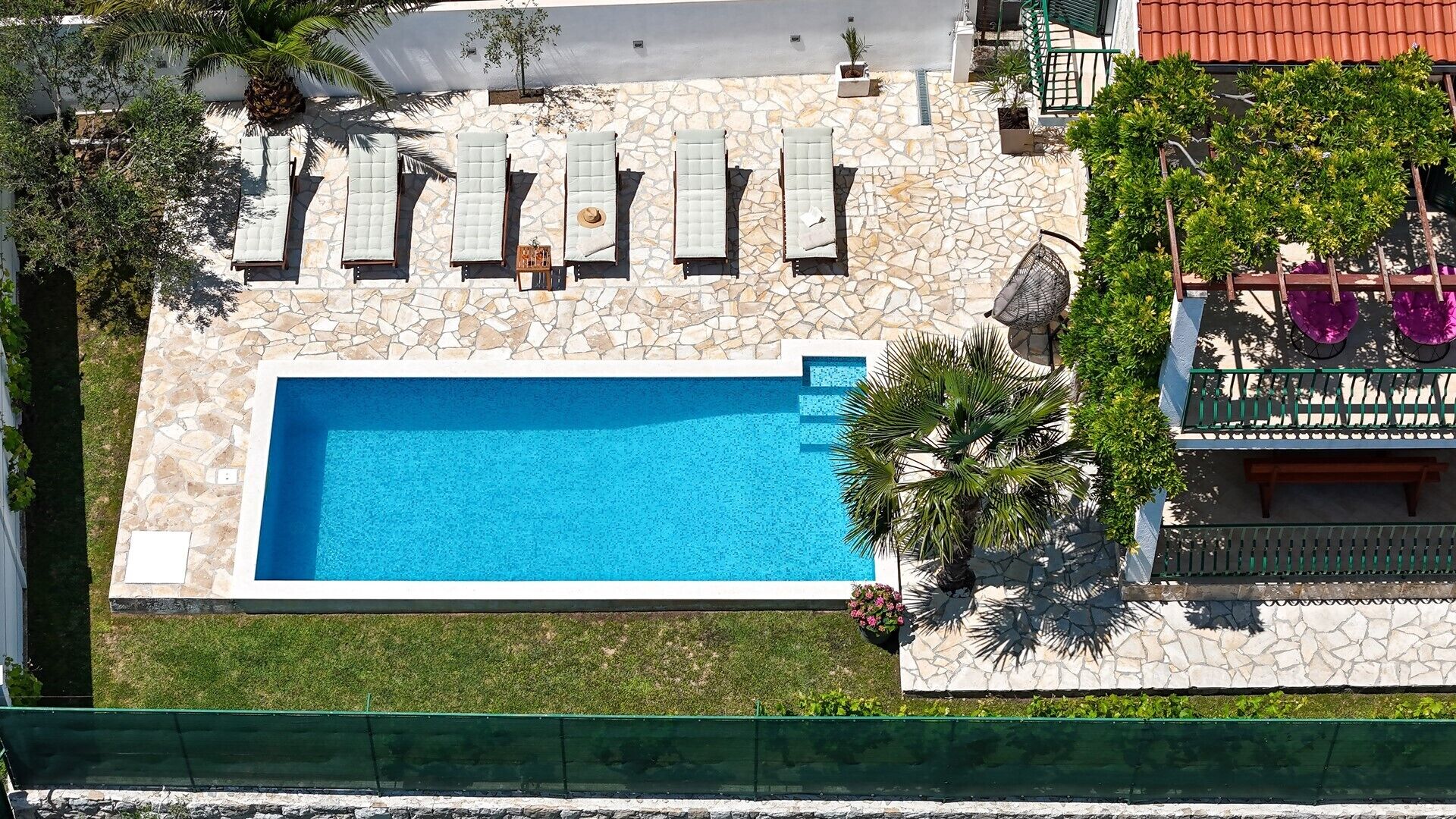 A swimming pool with lounge chairs and a stone wall.
