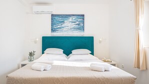 A bedroom with a teal headboard, white bedding, a painting of the ocean, and a bedside table with a lamp. - Villa Josip near Omiš, private pool (Gata)