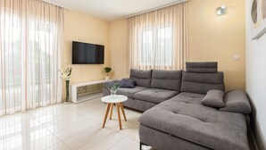 A modern living room with a grey sectional sofa, a white coffee table, and a flat-screen TV mounted on the wall. - Villa Josip near Omiš, private pool (Gata)