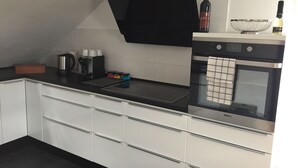 Moderni keittiö, jossa on sisäänrakennettu uuni, kahvinkeitin ja viinipullo.