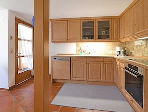 A kitchen with wooden cabinets, a dishwasher, a coffee maker, and an oven.