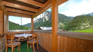 Un interno in legno con un tavolo e sedie, ampie finestre e vista sulle montagne.
