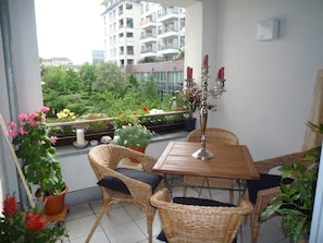 Enjoy a peaceful retreat on the balcony with a table, wicker chairs, and lush garden views.