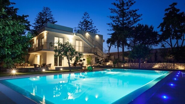 A modern two-story house with a swimming pool, surrounded by trees and a stone wall. - Apartment with heated saltwater pool, private garden, air conditioning, WiFi (Donnalucata)
