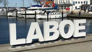 A marina with boats docked, a large sign reading 'LABOE,' and a building with a sign 'FISCH KUCHE.' - Penthouse vacation apartment "Auszeit" 100 m from the center. Beach, preferably with dog, WLan incl. (Laboe)