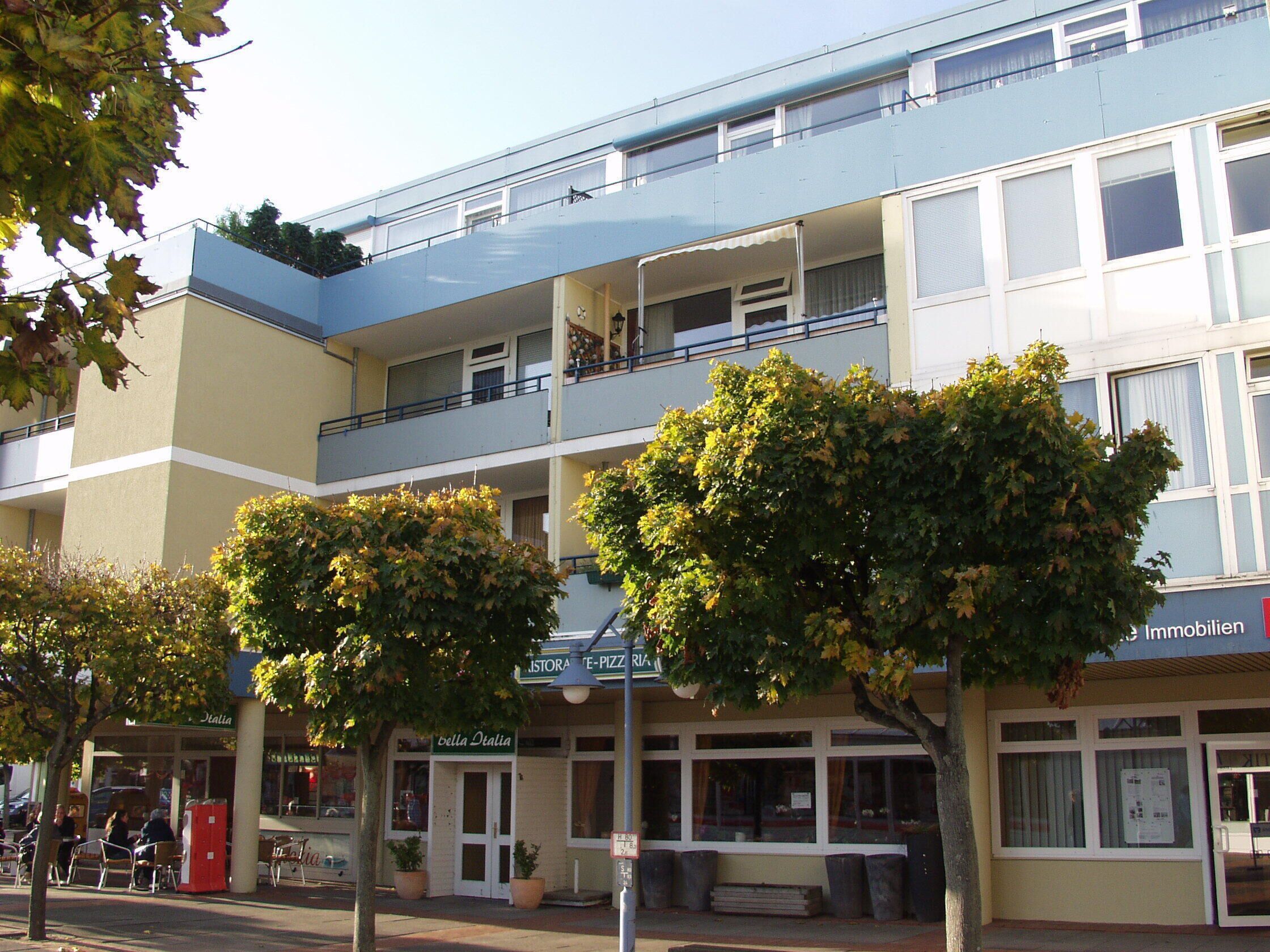 A multi-story building with balconies, a restaurant named "Bella Italia," and a sign for "Immobilien."