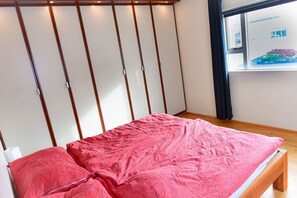 A bedroom with a bed, wooden slats on the wall, and a window with curtains. - Spacious and comfortable house at the shore (Akureyri)