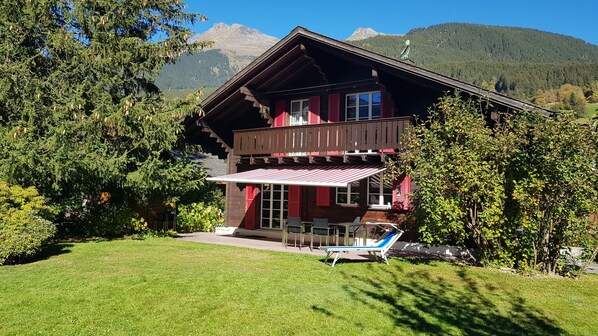 A chalet with a balcony, a covered patio, and a view of mountains.