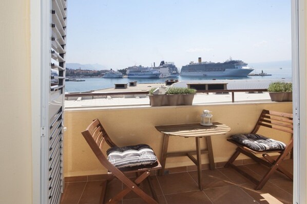 A balcony with two wooden chairs and a small table, overlooking a marina with several cruise ships. - ****Apartment Xenios with sea view, promenade, old town, balcony (Split)