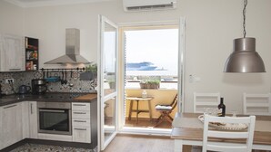 Eine moderne Küche mit einem großen Fenster, ein Essbereich mit Tisch und Stühlen sowie Meerblick.