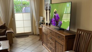 Una sala de estar con televisor, aparador de madera, una silla y un sofá.
