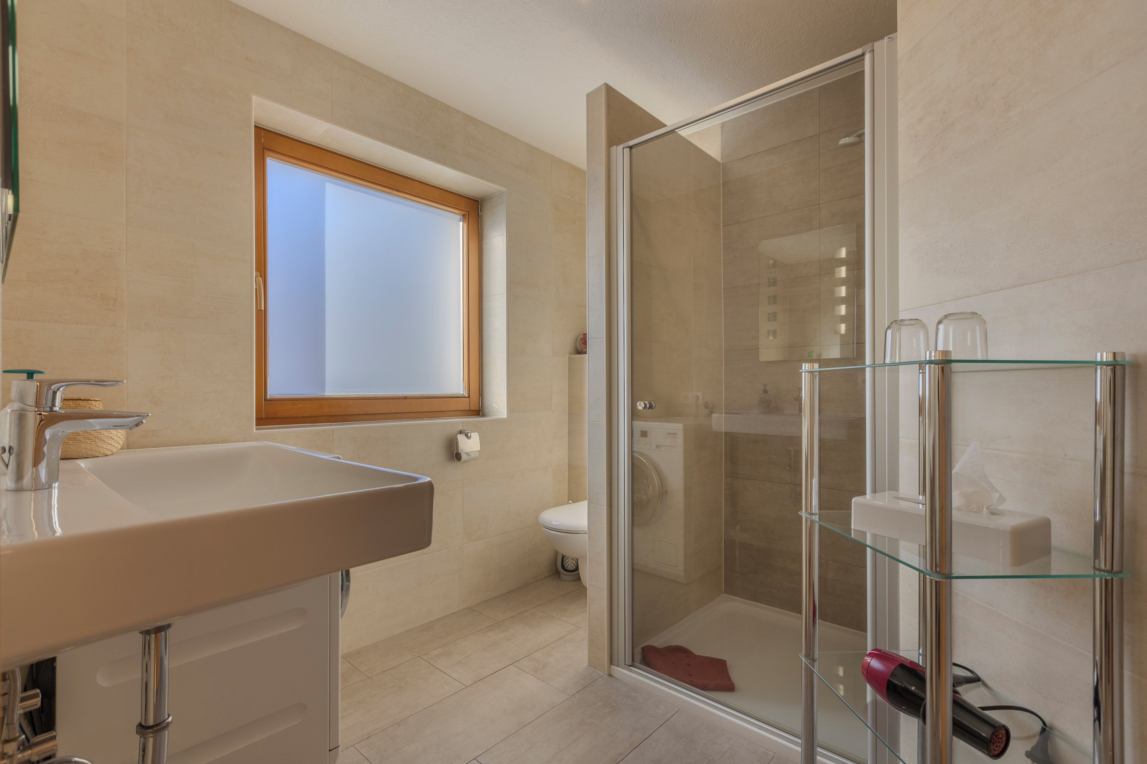A modern bathroom with a glass shower enclosure, a sink, and a toilet.