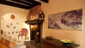 A cozy room with a fireplace, a dining area, and a large painting on the wall. - Lovely restored village house over Bogliaco Gargnano – very spacious (Gargnano)