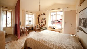 A bedroom with a large bed, a chair, a table, and a bookshelf. - Lovely restored village house over Bogliaco Gargnano – very spacious (Gargnano)