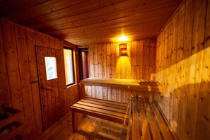 Een houten sauna met banken en een wandlamp.