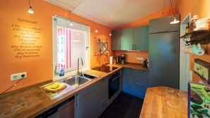 Une cuisine moderne dotée d’un plan de travail en bois, d’un évier en acier inoxydable et d’un four encastré. Une fenêtre offre une vue sur un bâtiment rose situé à l’extérieur.