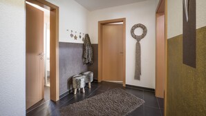 A hallway with a wooden door, a bench, and a rug.