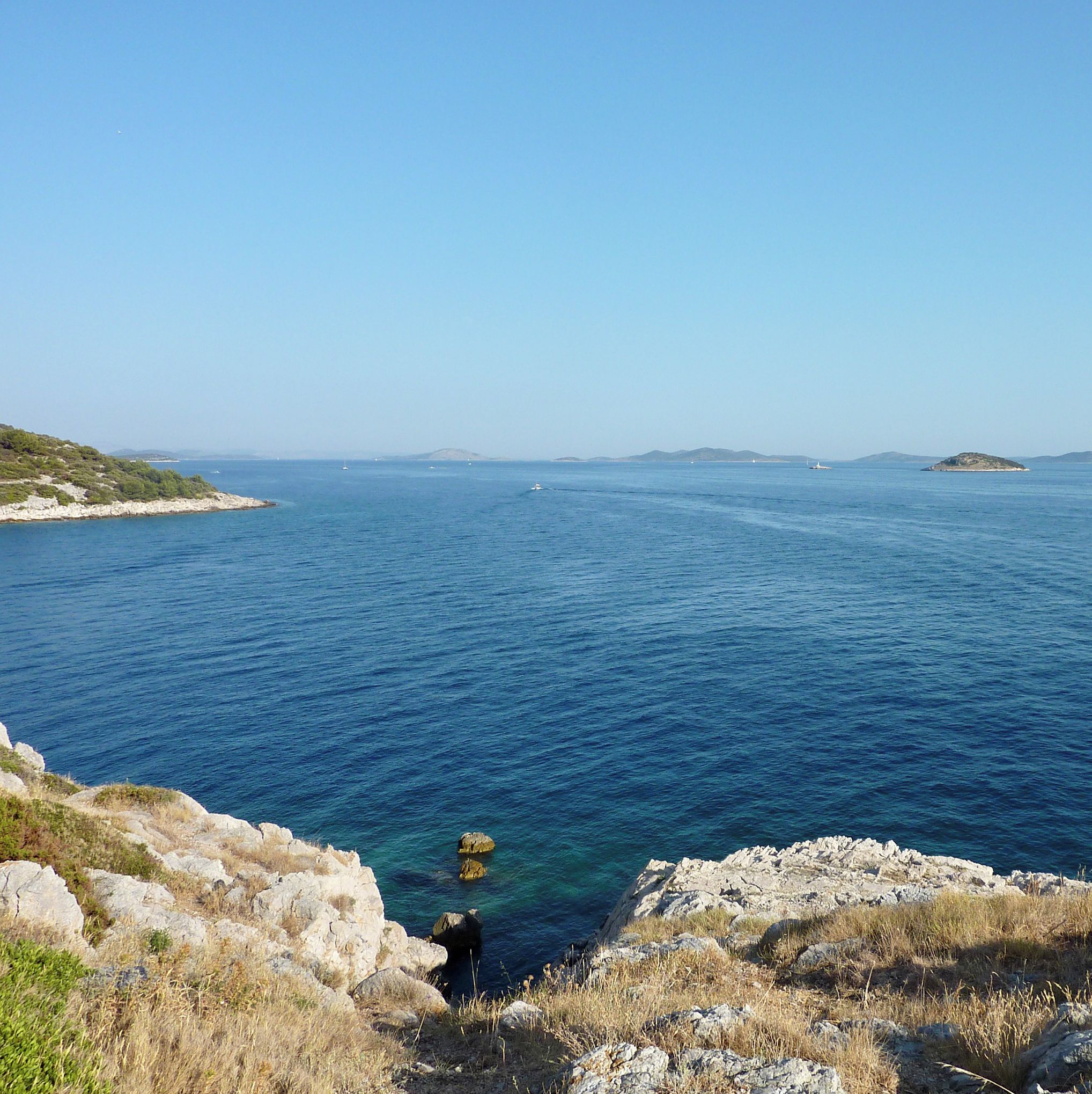 A coastal landscape with rocky terrain and clear blue sea.