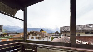 Een balkon met uitzicht op traditionele huizen en bergen op de achtergrond.