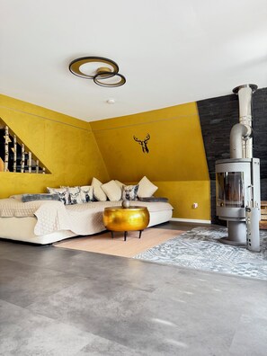 A modern bedroom with a bed, a decorative wall, a fireplace, and a unique ceiling light fixture.