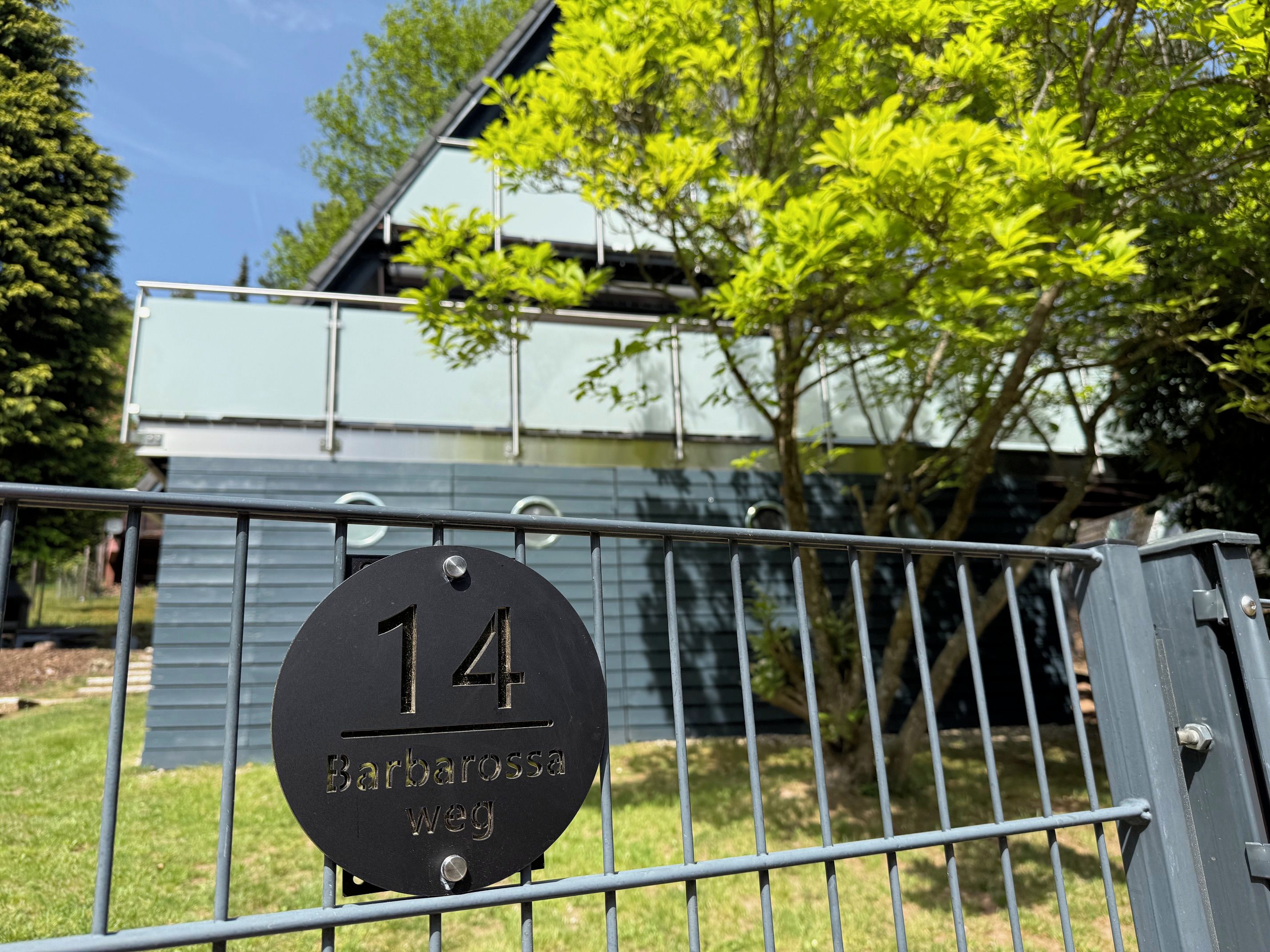 Um portão de metal com placa de número '14' e o nome 'Barbarossa Weg', indicando o nome da rua.